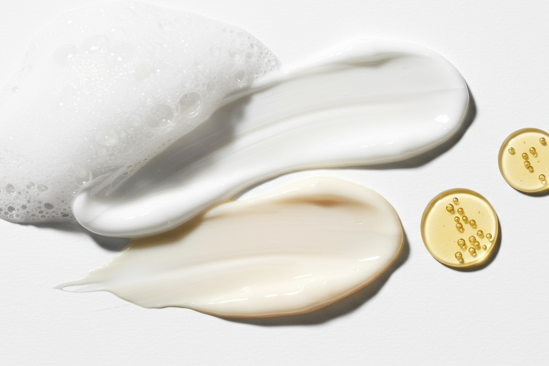 VAHNAI Barrier Repair — clean lab flat-lay of avocado cream, argan oil droplets, and jojoba leaf textures symbolizing lipid barrier support.