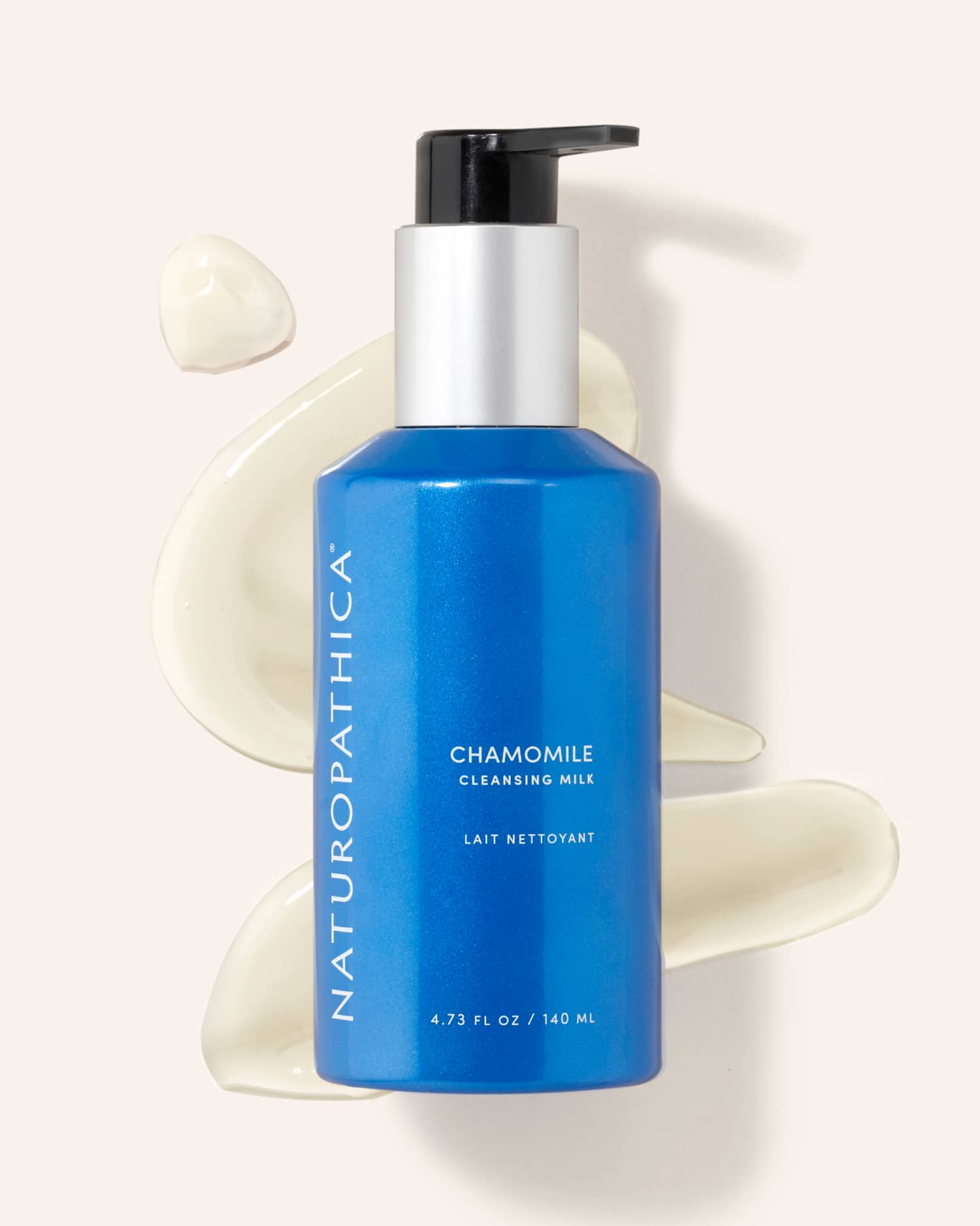 Bottle of Naturopathica Chamomile Cleansing Milk on a soft towel with chamomile flowers, styled as a calming facial cleanser for sensitive skin

