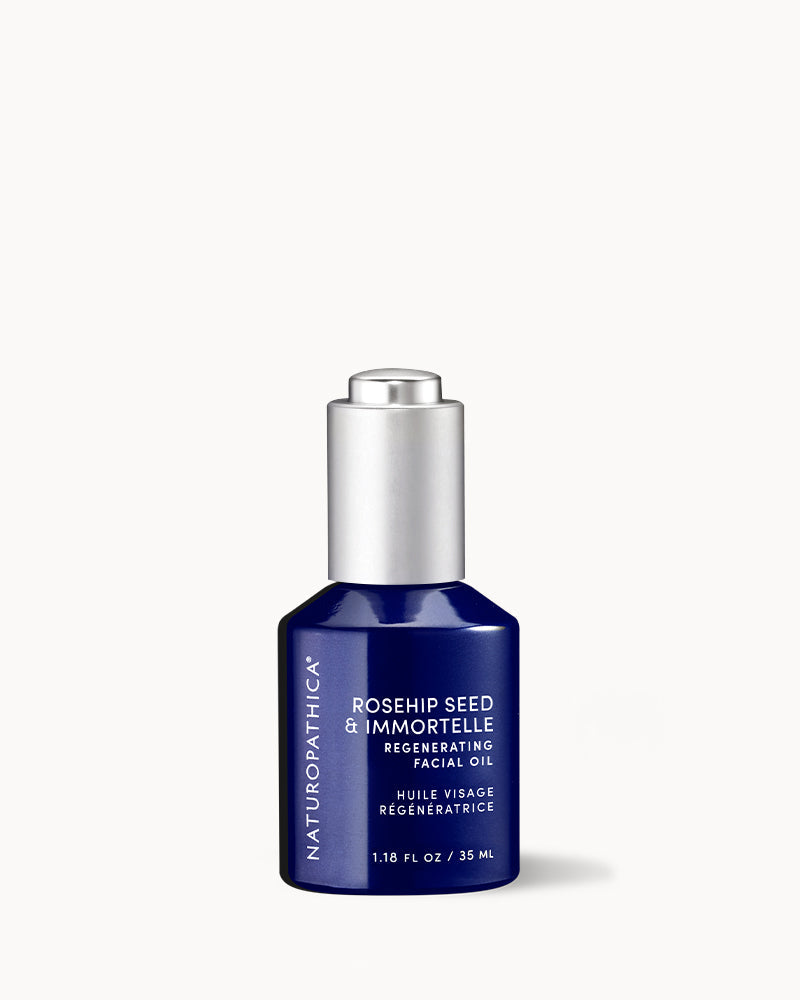 Amber glass bottle of Naturopathica Rosehip Seed & Immortelle Regenerating Facial Oil on a neutral background with botanicals, promoting hydration and glow