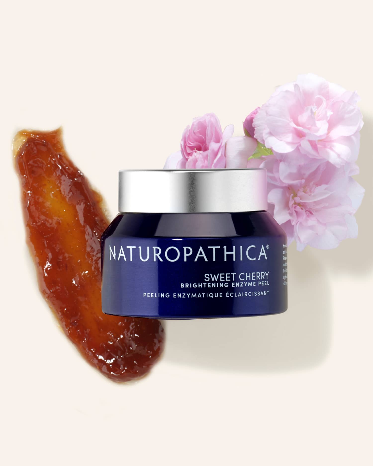 Jar of Naturopathica Sweet Cherry Brightening Enzyme Peel open beside fresh cherries on a marble surface, styled as a radiant skin resurfacing mask