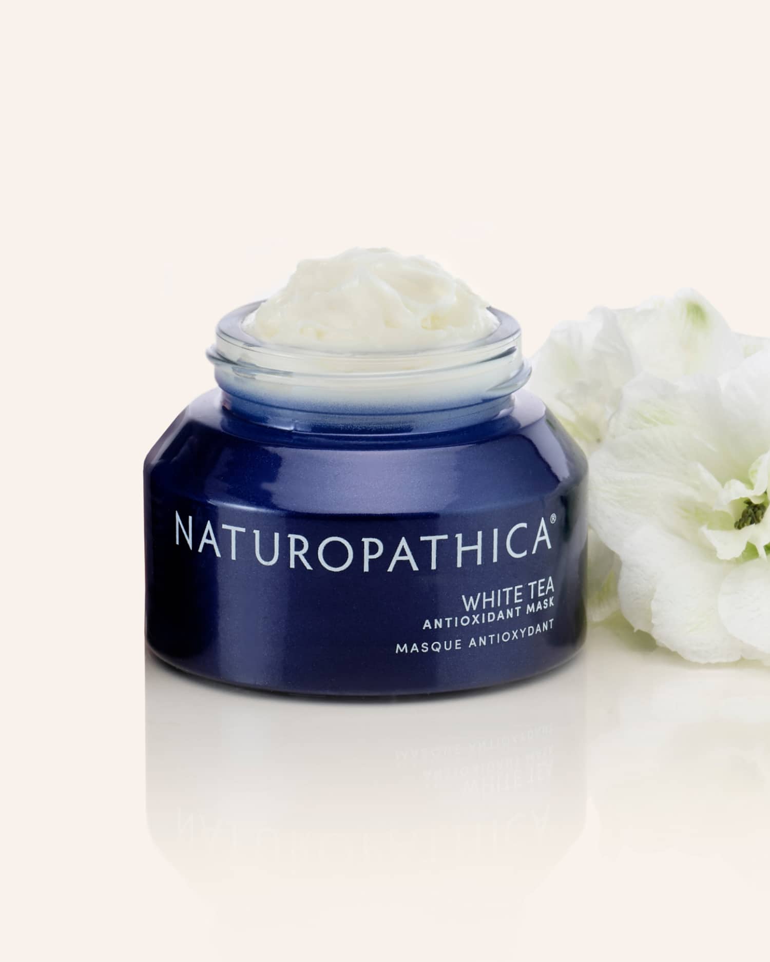 Jar of Naturopathica White Tea Antioxidant Mask open beside white tea leaves and a soft towel, styled as a calming hydration treatment for stressed skin