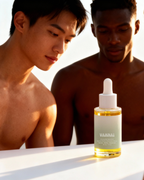 Two men looking at a bottle of VAMN skincare serum on a reflective surface.