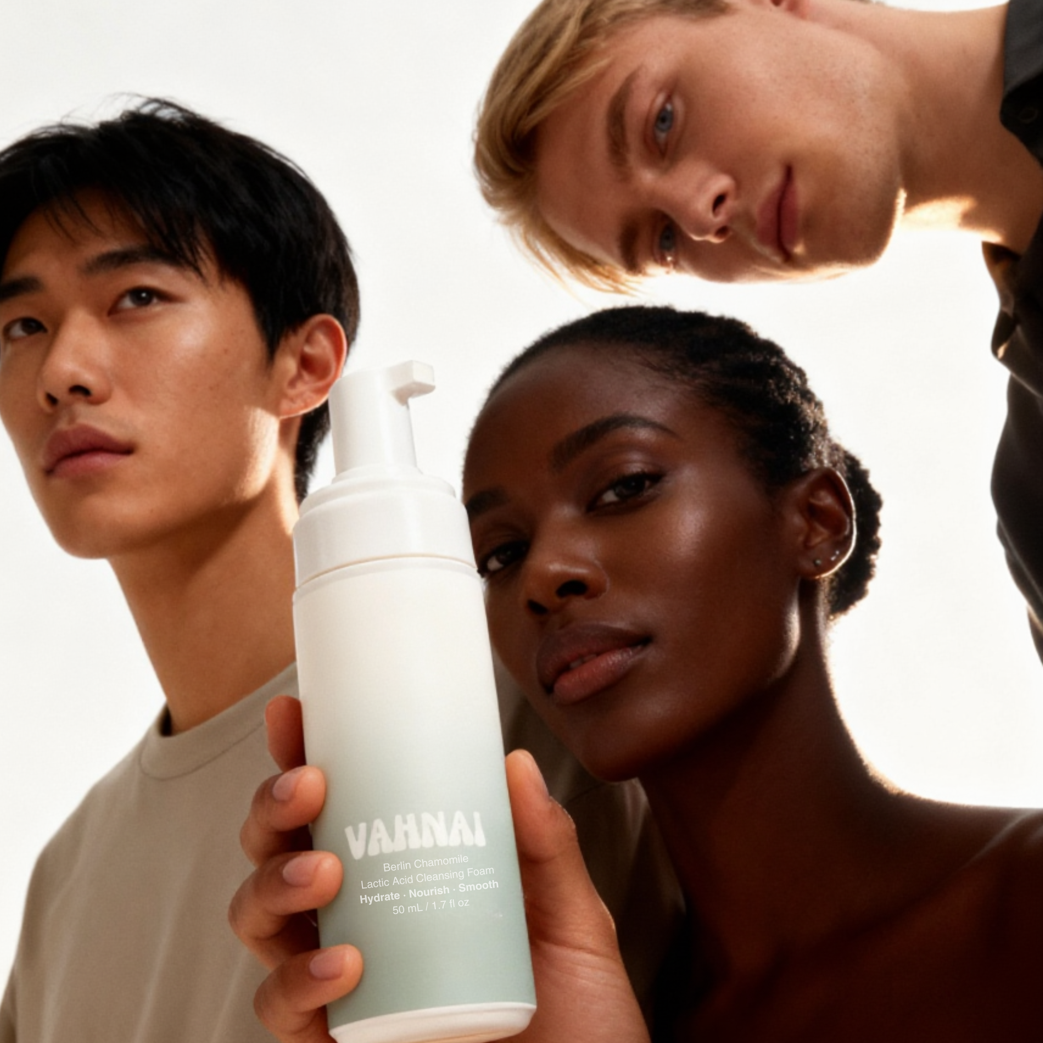 Flatlay of VAHNAI Berlin Chamomile & Lactic Acid Cleansing Foam with chamomile flowers and foaming cleanser texture on white background.

